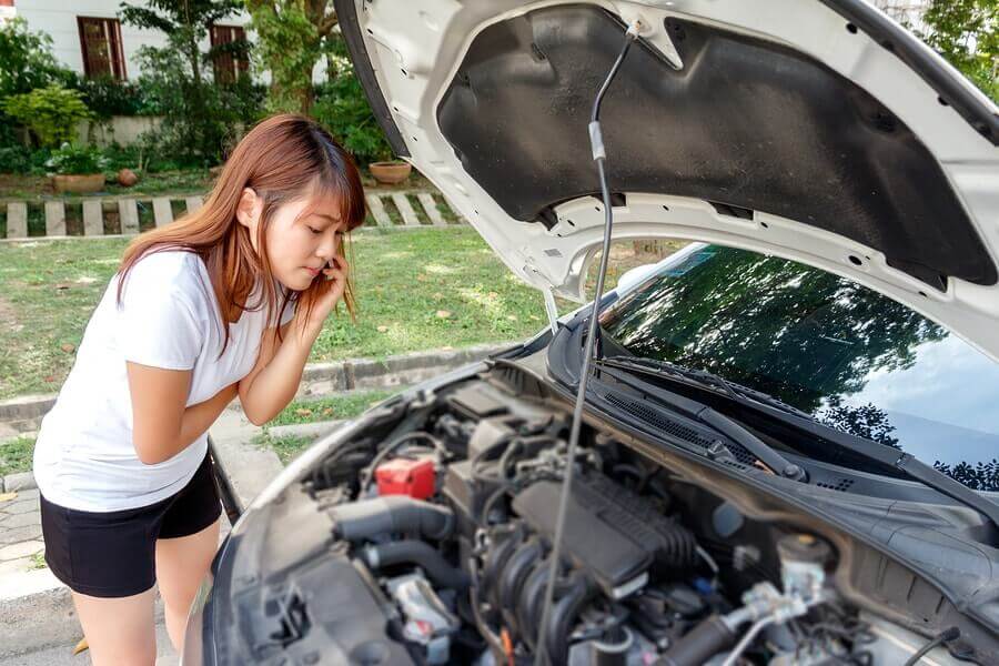 A woman looking under the bonnet of her car