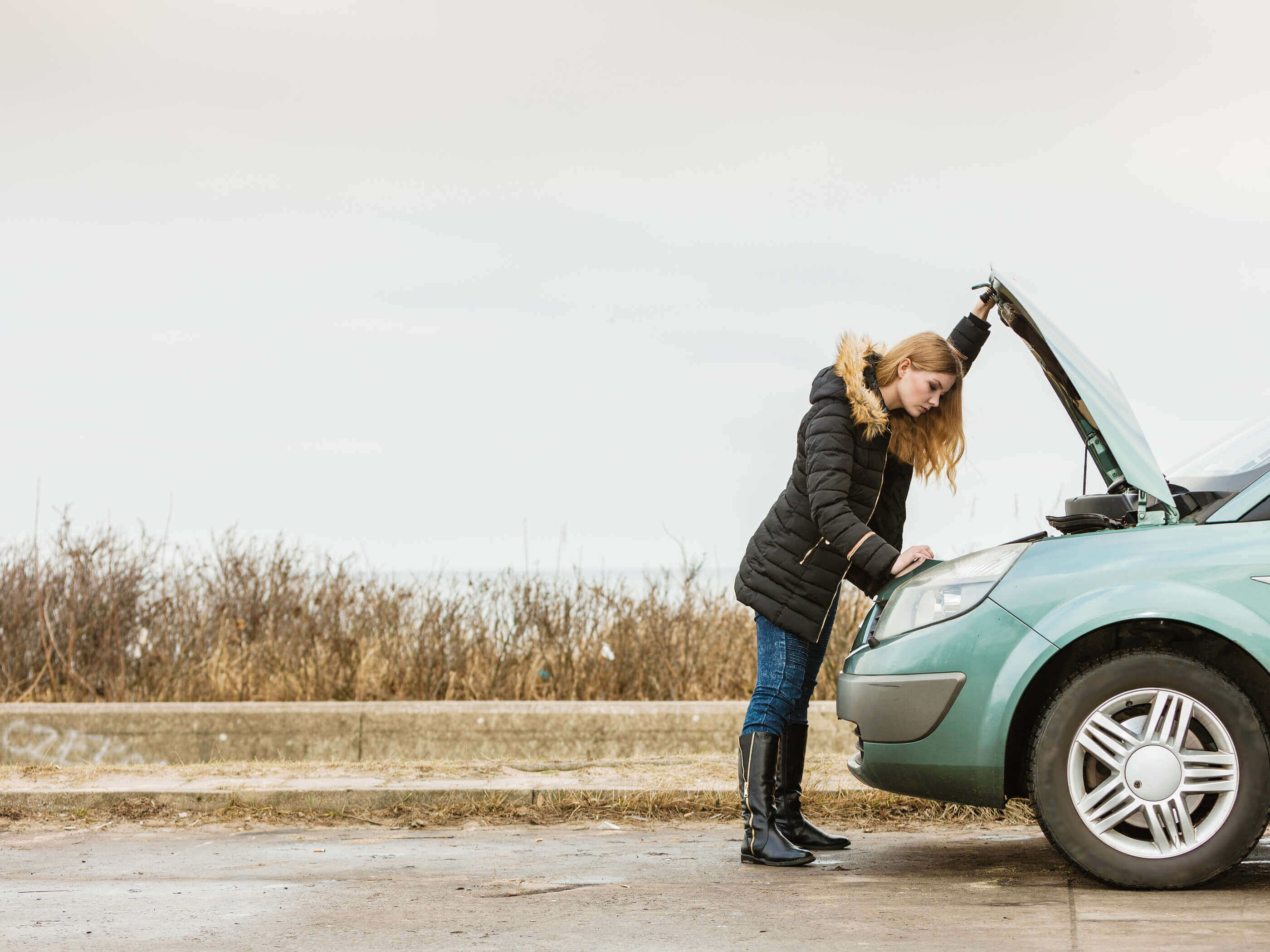 A woman looking under the bonnet of her car